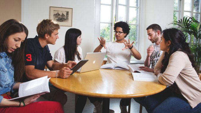 Studenten vieler Nationen sitzen um einen Tisch herum.