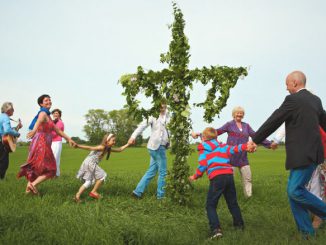 Eine Familie tanzt in Schweden um die Midsommarstange.