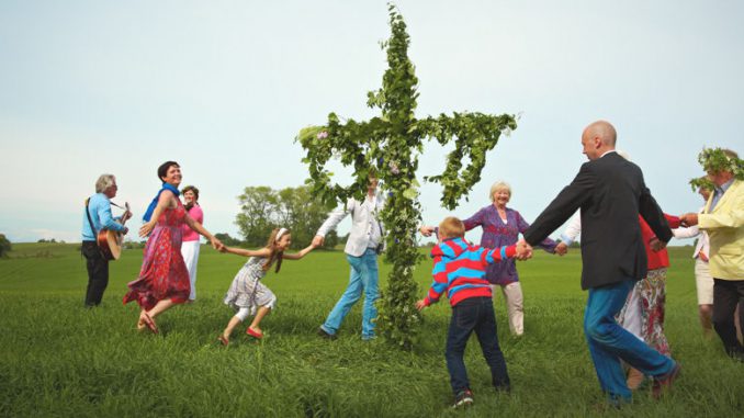 Eine Familie tanzt in Schweden um die Midsommarstange.