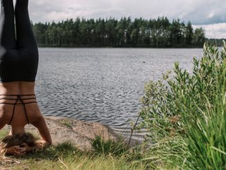 Eine Frau beim Yoga: Kopfstand vor dem schwedischen See.